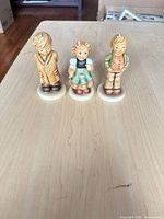 Front view of three Goebel Hummel child figurines on table