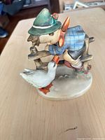 Front three-quarter view of figurine showing boy, fence and goose