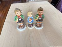 Front view of three porcelain figurine ornaments on bases