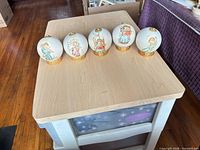 Front view of all five spherical porcelain musical figurines on table