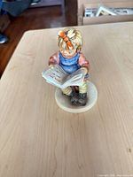Front view of porcelain girl reading on cream base