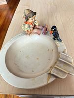 Top view of ashtray showing boy, crow, cigarette rest and glued crack