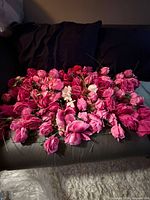 Cluster of assorted pink artificial flowers spread on sofa