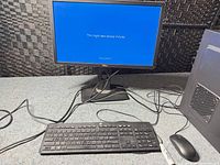 Desktop setup with Dell monitor displaying Windows update screen, keyboard, mouse, and tower visible