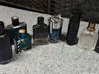 Row of eight assorted empty designer fragrance bottles on fabric surface