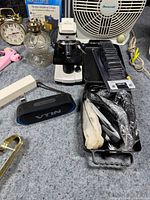 Overall view showing microscope, speaker, clock, oil lamp, fan, glue gun, clipper case and accessories