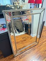 Front view showing rectangular mirror with beveled border and beaded champagne frame