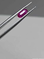 Ruby held in tweezers showing profile and color