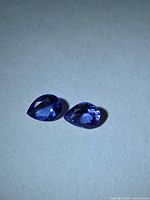 Two pear-cut deep blue Tanzanites on neutral background