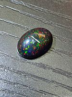 Front view of oval black opal showing pinfire colors