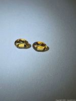 Two oval yellow gemstones on white background