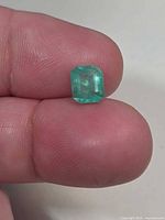 Octagon-cut emerald on fingertip, showing overall size and color