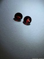Both round garnets side by side under focused light