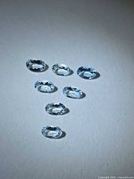 Seven oval light-blue gemstones arranged on a white background