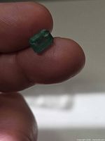 Emerald held between fingers showing size and color