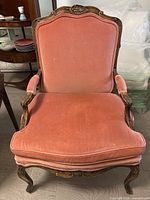 Front view of pink upholstered Bergere chair showing carved frame and cushion