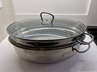 Nested stainless steel roasting pan, shallow lid pan, and glass lid