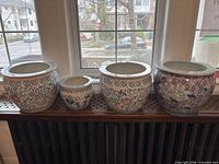 four ceramic planter pots lined up on shelf