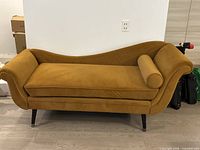 Front view of mustard chaise lounge, bolster pillow visible