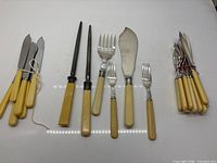 Group view showing fish knives, sharpening steels, serving pieces and bundled forks/knives