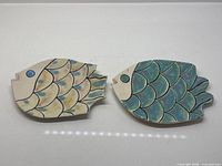 Top view of both ceramic fish plates showing painted scale designs