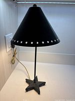 Full view of black metal table lamp with star punched shade