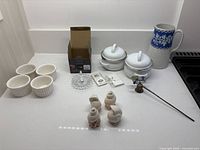 All items arranged on countertop showing ring holder, ramekins, soup bowls, jug, shakers, flower decoration, card pack