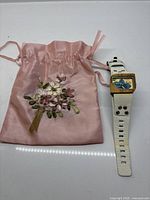 Watch beside pink satin pouch
