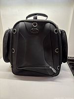 Front view of black motorcycle bag showing logo, front pocket and D-ring anchors