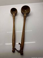 Front view of both wooden olive scoopers showing bowl size difference and handles