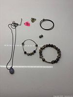 Group shot showing necklace, two bracelets, charms, clasp, clasp openers