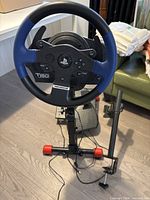 Racing wheel mounted on stand with pedals and monitor arm visible