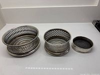Three silver plate pierced wine coasters, large to small
