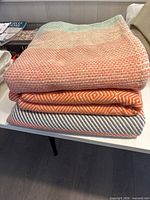 Three folded throw blankets stacked on table showing colours and woven textures