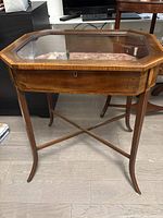 Full view of wooden glass-top display table showing octagonal top and legs