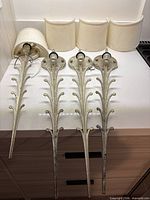 Four metal wall sconces with shades laid out on counter