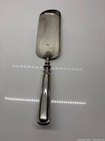 front of silver-plated crumb scraper showing blade and handle