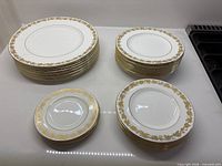 Stacks of dinner, luncheon and dessert plates showing gold rim pattern