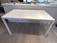 Front angled view of the white rectangular table showing top surface and legs