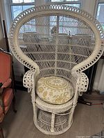 Front view of white wicker peacock chair with cushion