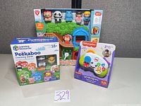 Front view of all three boxed toys: Fisher-Price controller, Learning Resources Peekaboo Farm, PlayGo animal playset