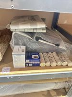 Shelf showing boxed BP monitors, bandage rolls, folded MegaMover sling