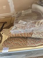 Braided items on shelf including chair pads in plastic and folded rug