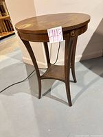 full view of round walnut-finish side table showing legs and lower shelf