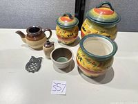Full lot showing three canisters, teapot, bottle, bowl, owl trivet