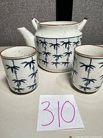 Front view of teapot and both cups showing blue bamboo pattern