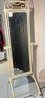 Full view of ornate cream metal cheval mirror on stand