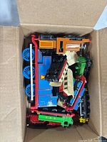 Box containing mixed toy trains and cars