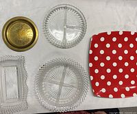 Overview of five serving pieces laid out: brass plate, two round glass platters, rectangular glass tray, red polka-dot plate