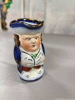 Front view of miniature Allertons Toby jug showing face, torso, colors, gilding